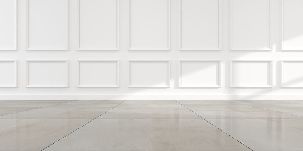 A room with white paneled walls and large, light gray tiled flooring, illuminated by natural light from an unseen window on the right, showcases the quality craftsmanship of a renowned flooring company in Mississippi.
