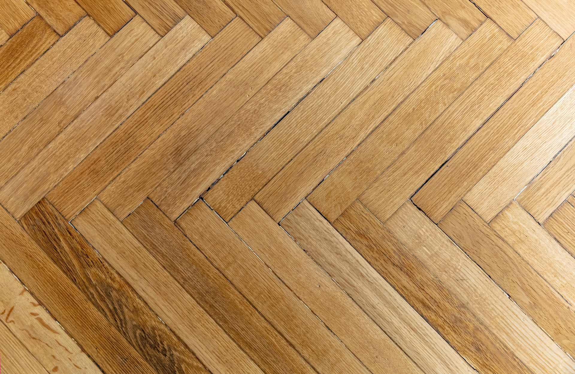 Experience the craftsmanship of our flooring company with this herringbone-patterned wooden floor, featuring a stunning mix of light and dark brown tones. Perfectly suited for any home, especially those in Louisiana seeking a touch of elegance.